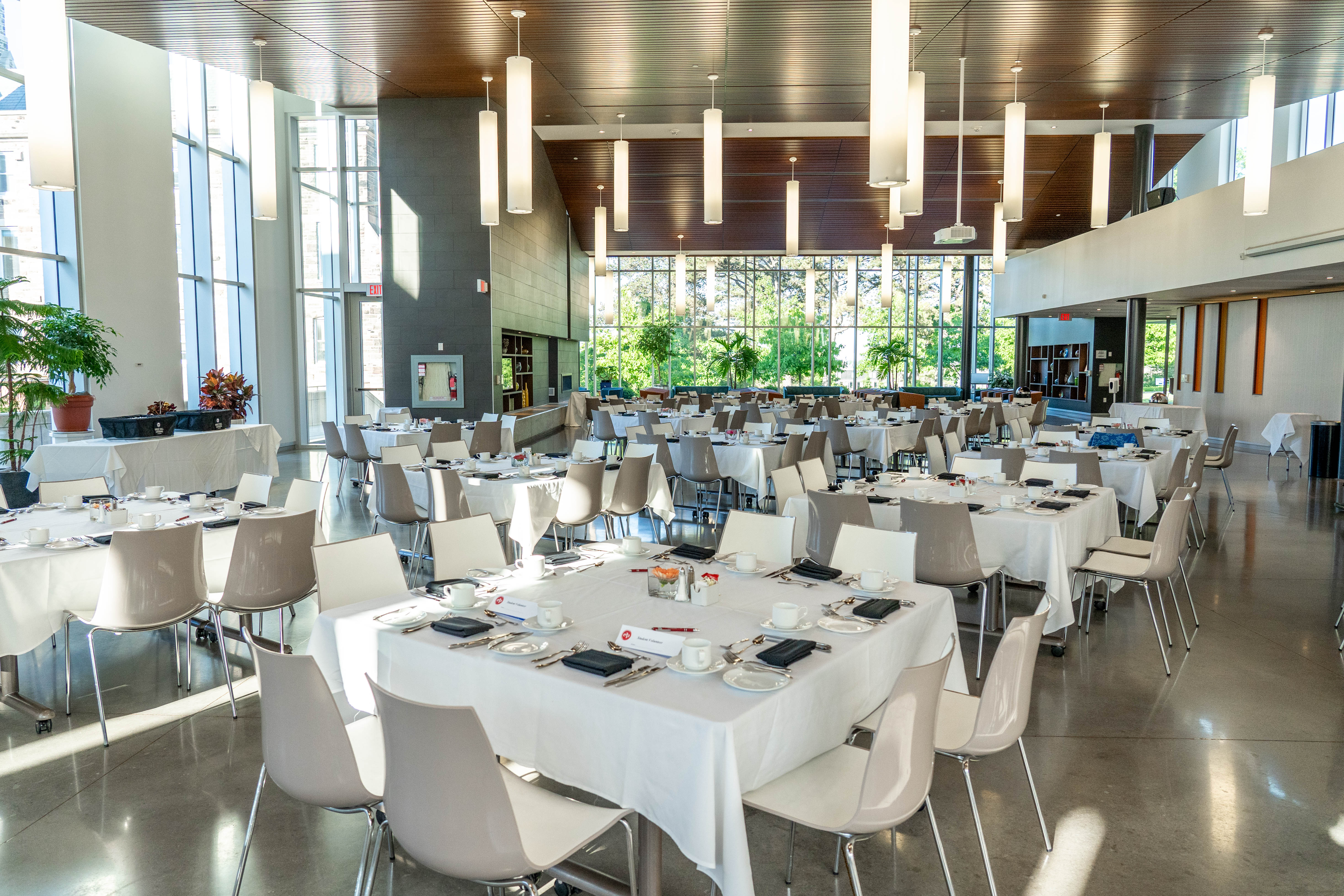 A modern event hall set for a banquet, with round tables, purple decor, lime green chairs and branding displayed on screens.